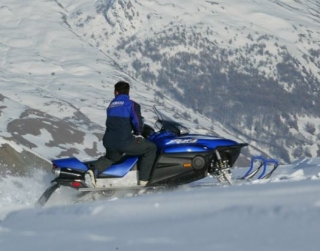  Siga la moto de nieve instructor en la montaña